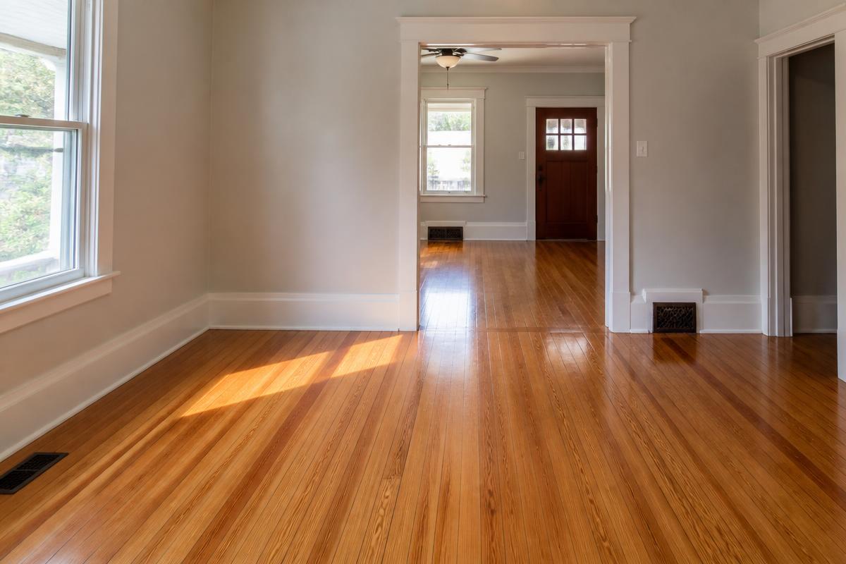Original oak hardwood floors sanded and refinished in an older Andrews, NC home, showing original trim and tall baseboards with sunlight across the boards