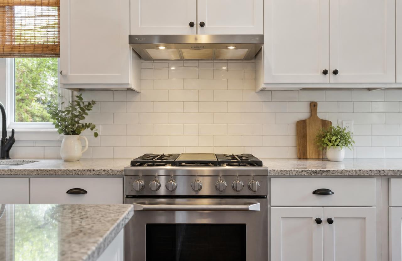 White subway tile kitchen backsplash with light gray grout installed behind a stainless range and hood in a Blairsville, GA kitchen