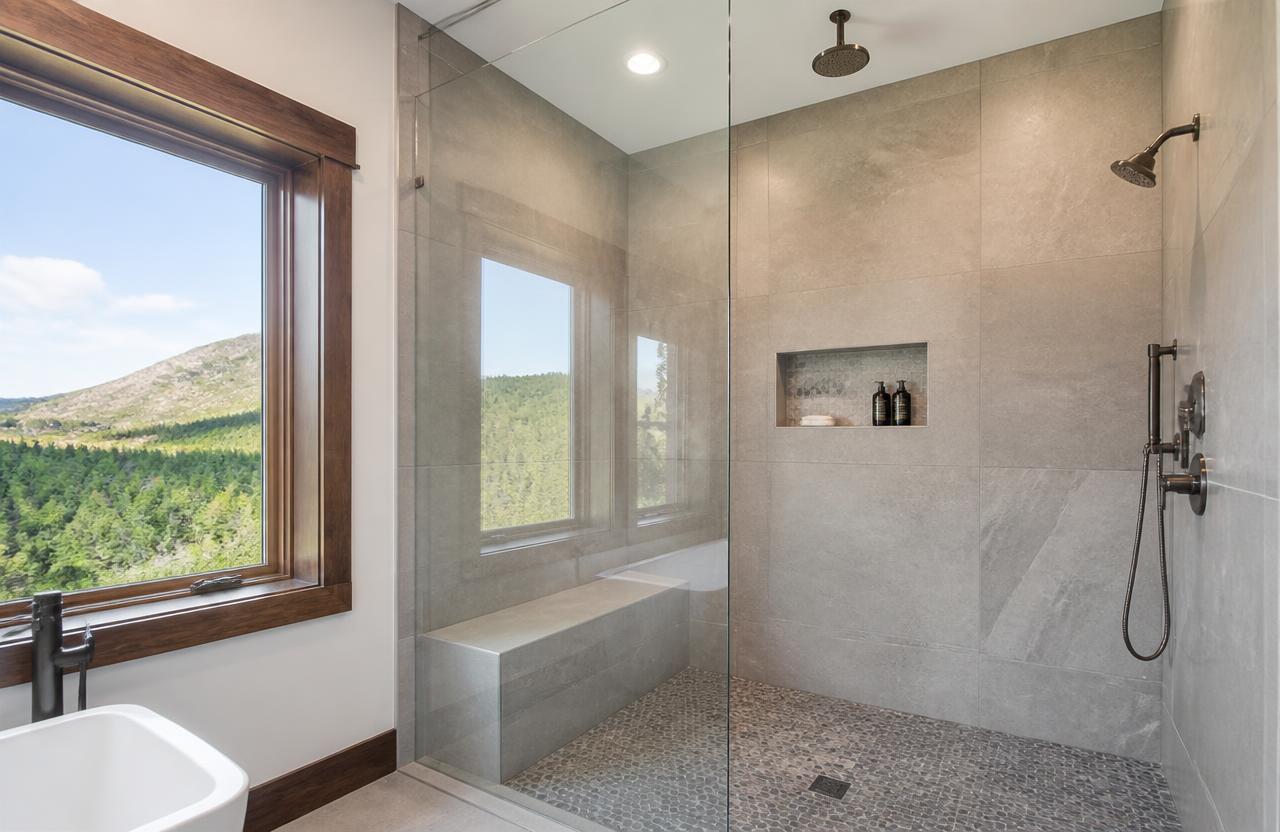Custom walk-in tile shower with bench, niche and glass panel in a Dahlonega, GA mountain home master bathroom by O-T Tile and Flooring